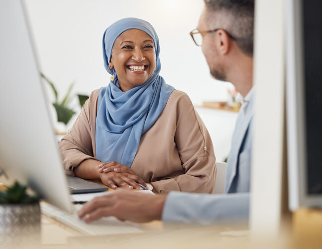 Muslim woman sitting next to white male working