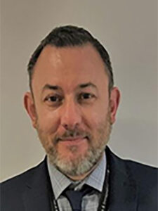 Photo of Darren Blakemore wearing a grey suit and tie and light grey shirt