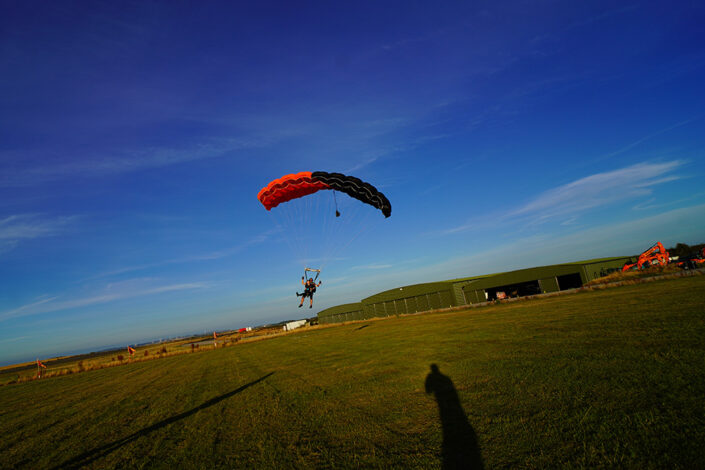 Photo of Stephanie and her skydiving instructor having just landed with the parachute canopy above her