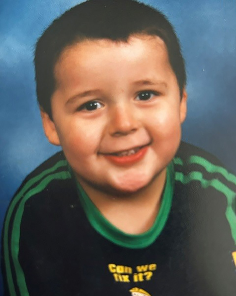 Photo of Sean as a child aged about four with short dark hair and wearing a blue jumper with green stripes